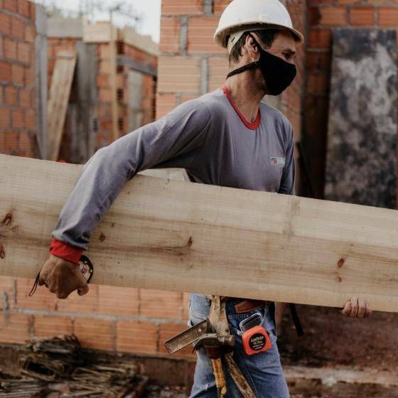 Profissional da Medeiros carregando tábua de madeira na obra