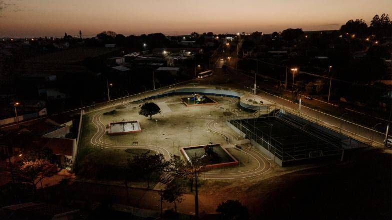 Vista aérea da Praça Daniel Folle à noite, com a quadra de grama sintética